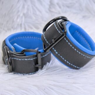 Black leather wrist cuffs with blue padded lining, blue contrast stitches, and black hardware.