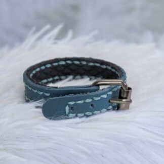 A small turquoise and black strap of leather with gunmetal hardware
